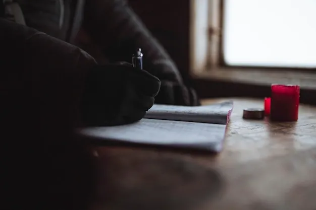 osoba pisząca w dzienniku przy oknie