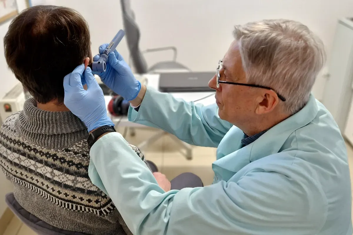 Lekarz bada ucho pacjenta, co jest pierwszym krokiem, by dowiedzieć się, jak załatwić aparat słuchowy na NFZ.