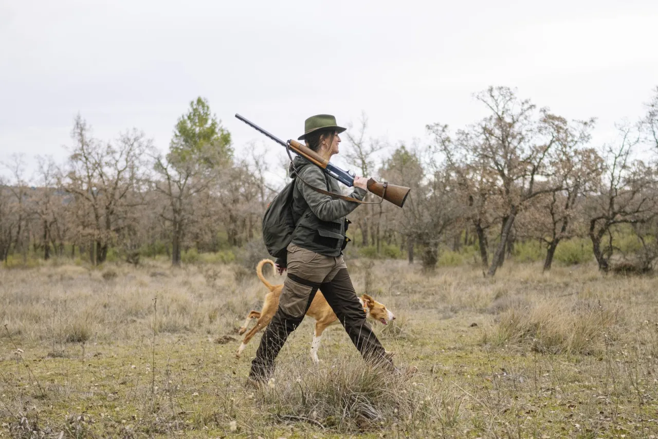 Myśliwy z psem w lesie, z bronią na ramieniu. Czy myśliwy jest zdolny do oceny stanu zdrowia zwierzęcia?