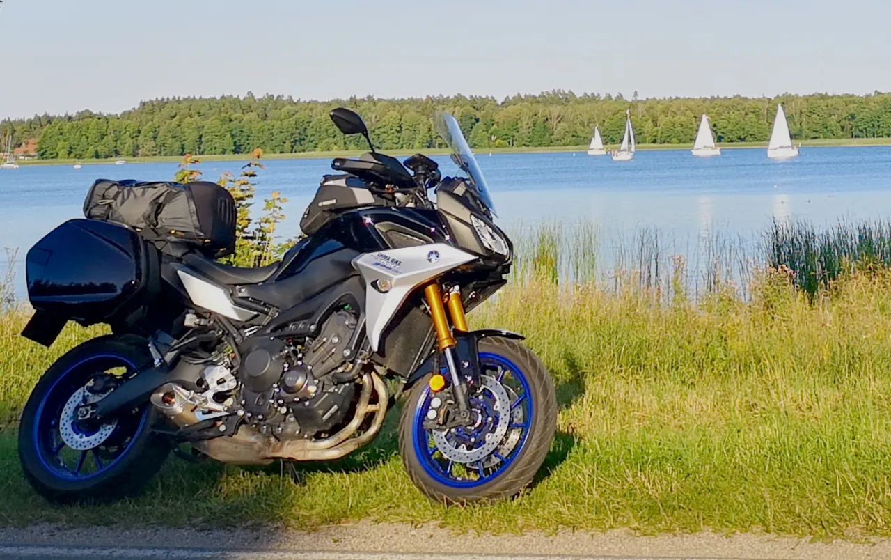 Motocykl na krętej drodze na Mazurach z jeziorem w tle