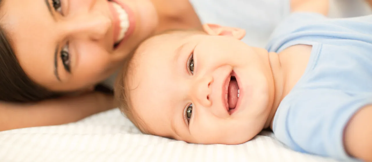 uśmiechnięte dwumiesięczne niemowlę patrzące na mamę