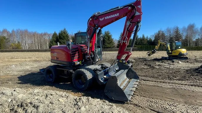 koparka ustawiona na płaskim terenie z opuszczoną łyżką