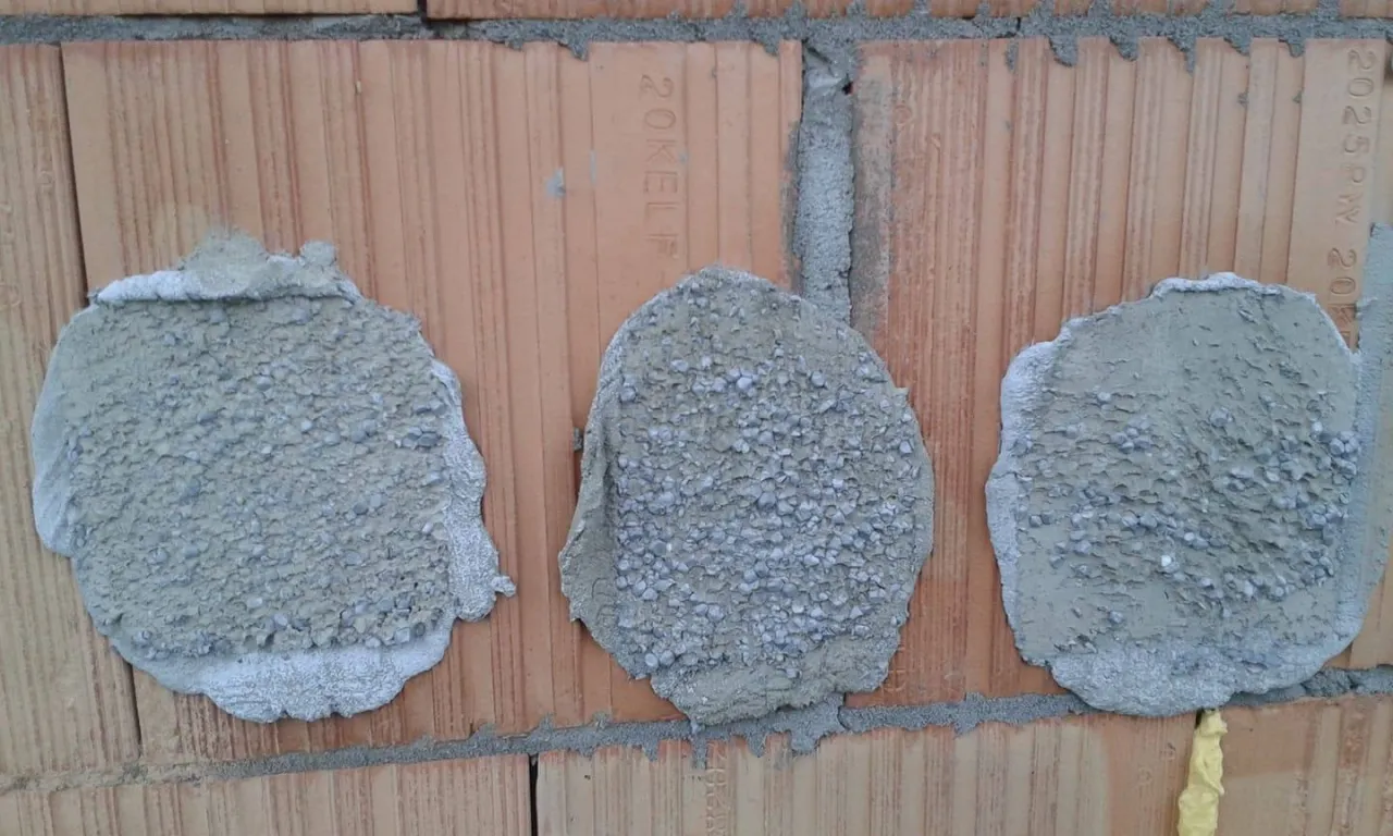 Trzy plamy zaprawy z kulkami styropianu na ceglanej ścianie. Tak wygląda przygotowanie do tego, kiedy kołkować styropian.