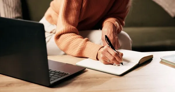 osoba pisząca list zamyślona nad kartką papieru