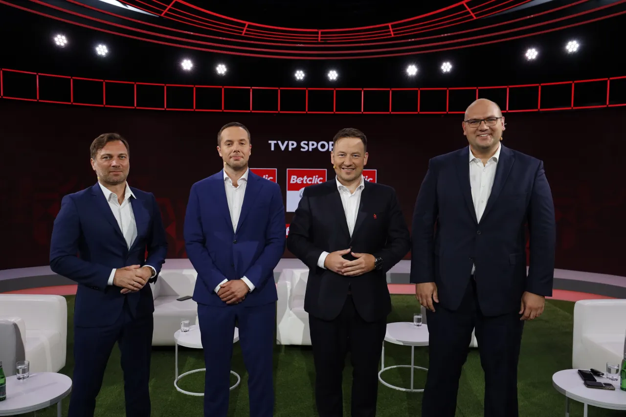 Czterech mężczyzn w garniturach na tle studia TVP Sport. Dyskutują o tym, o której mecz piłki nożnej.
