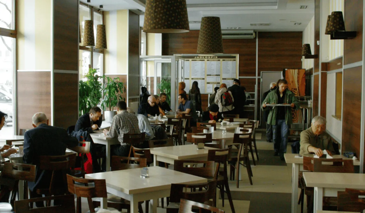 Ludzie jedzą obiad w restauracji w Warszawie. Widać menu, stoliki i krzesła.