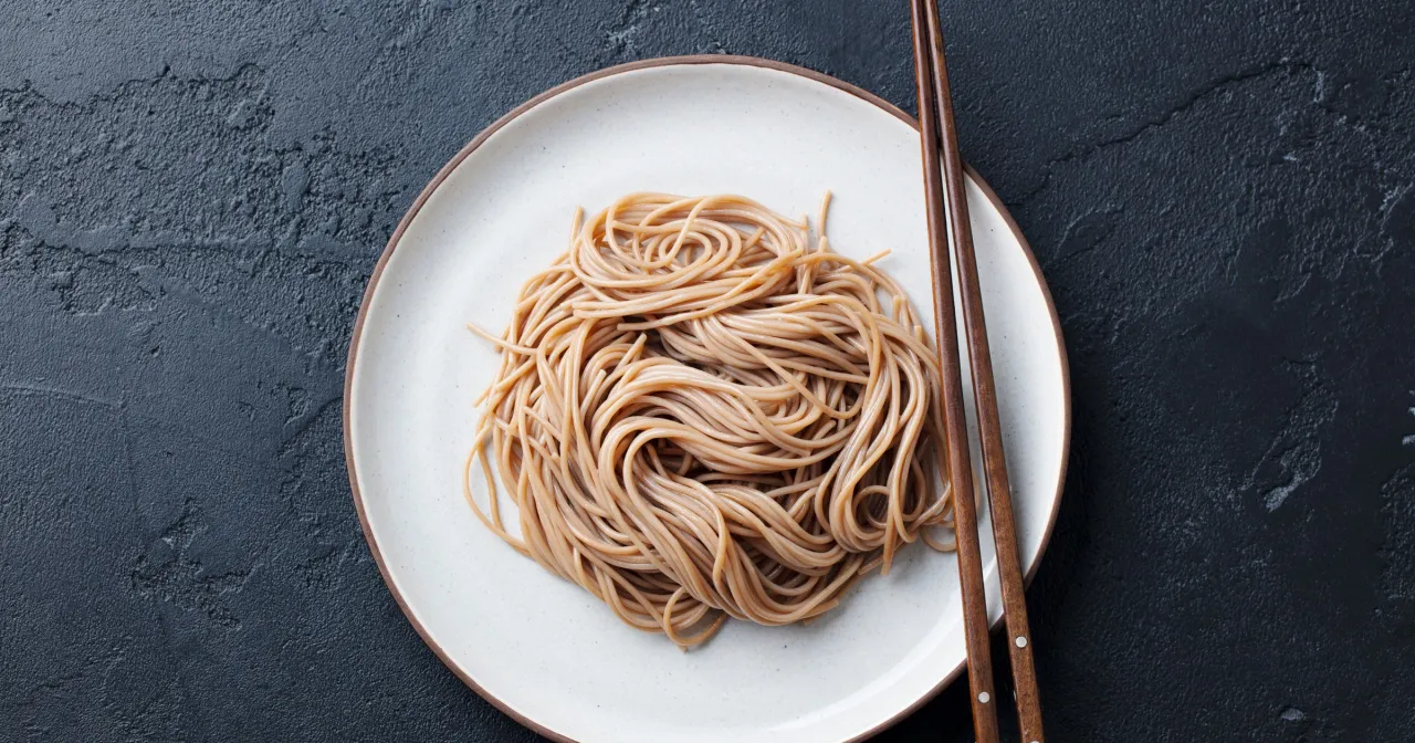 Porcja makaronu sojowego na talerzu z pałeczkami. Zastanawiasz się, ile kalorii ma makaron sojowy?