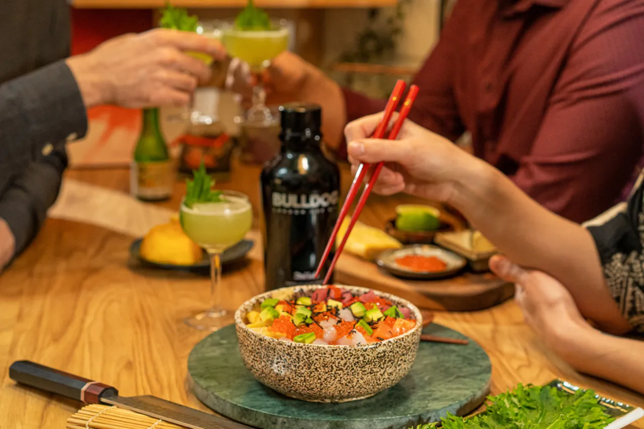 Kolorowe chirashi zushi z łososiem, tuńczykiem i awokado, podane z drinkami i butelką ginu.