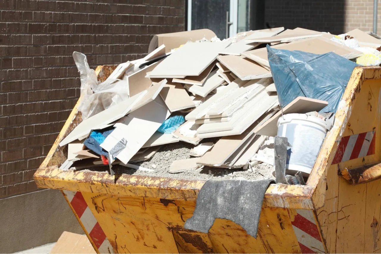 Kontener budowlany pełen odpad&oacute;w, w tym płyt gipsowo-kartonowych i folii. Zastanawiasz się, gdzie wyrzucić styropian? Ten kontener to miejsce na odpady budowlane.