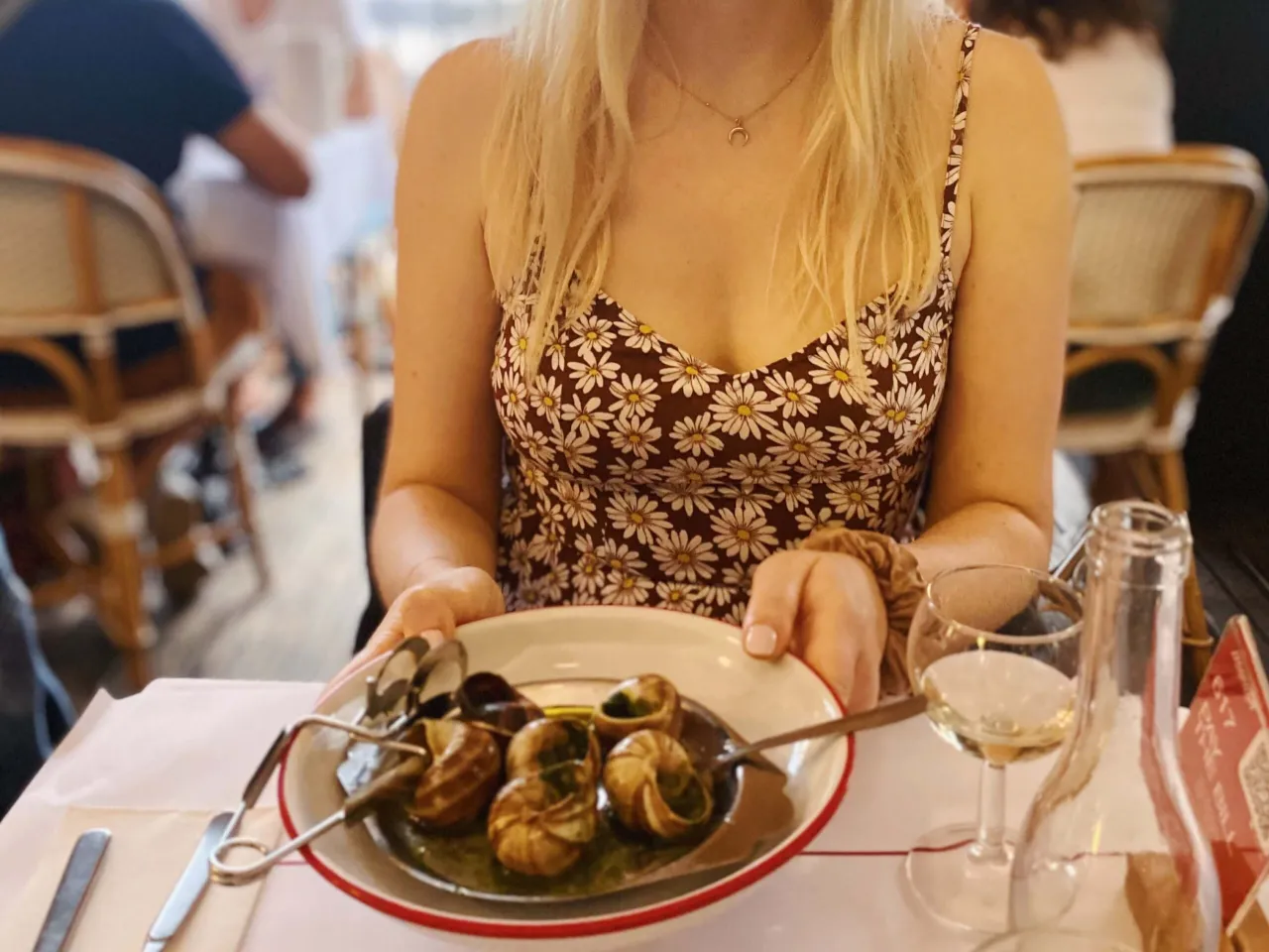 Kobieta serwuje ślimaki w czosnkowym sosie, jedno z charakterystycznych potraw kuchni francuskiej.