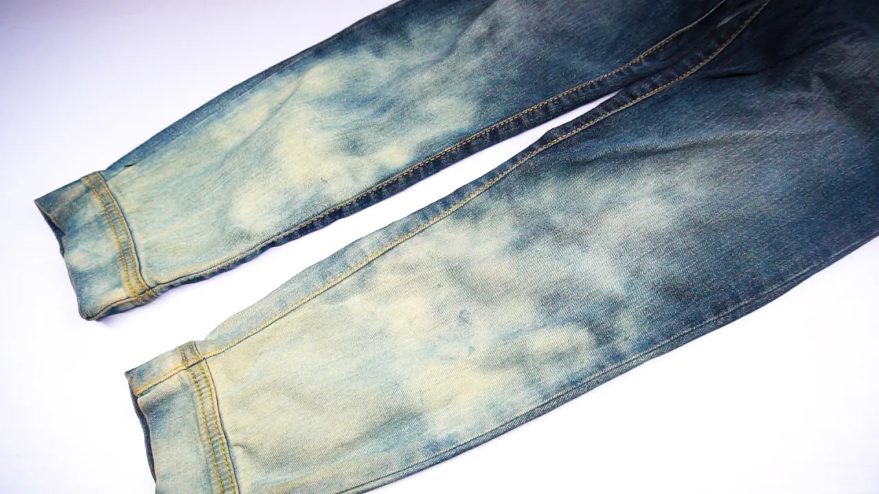 flat lay of items for bleaching jeans: bleach, rubber gloves, bucket, jeans