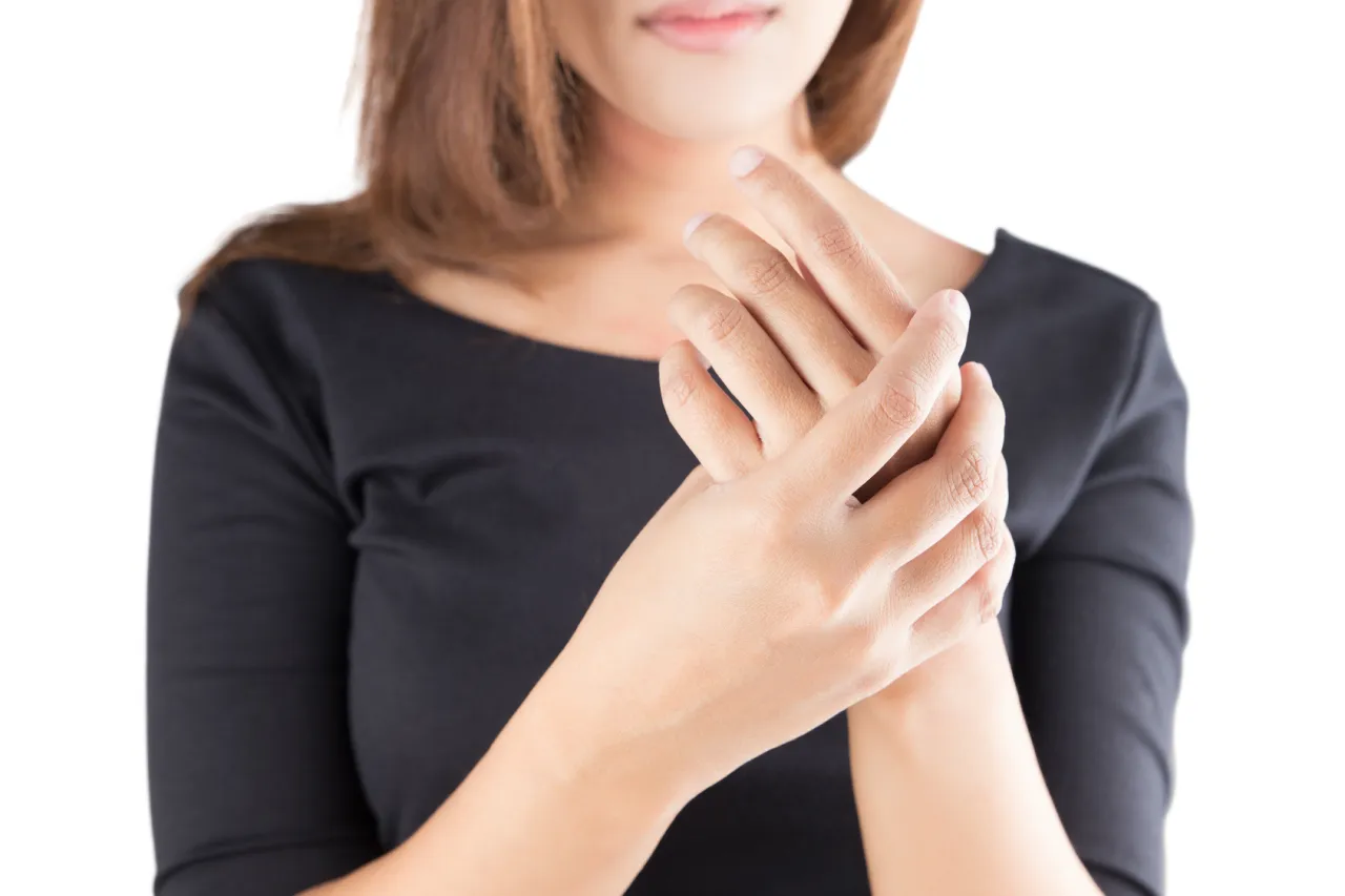 Kobieta trzyma się za nadgarstek, pokazując, jak wygląda skręcony nadgarstek.