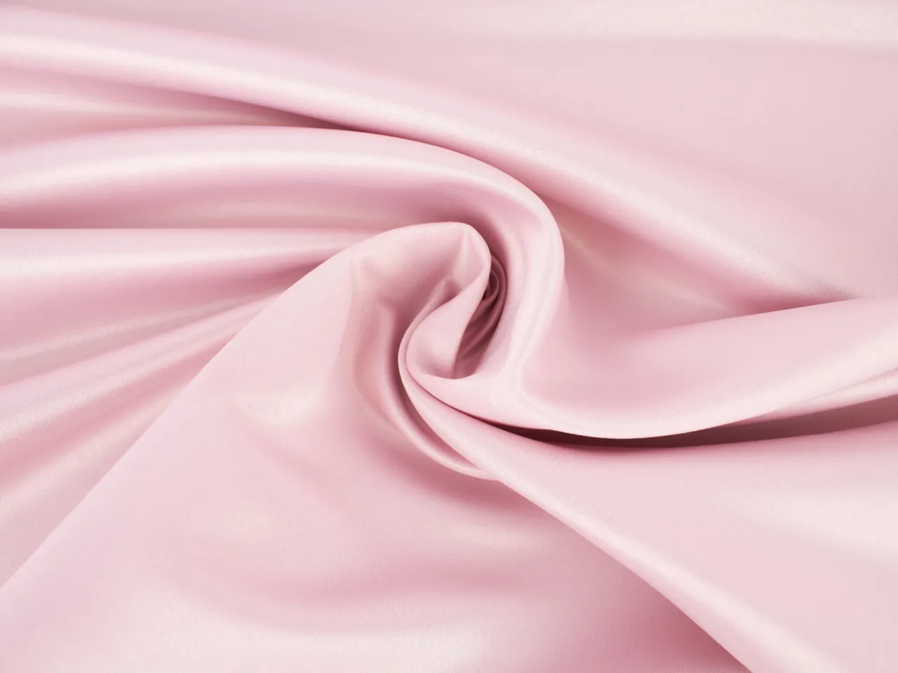 Gładki, r&oacute;żowy sztuczny jedwab układa się w miękkie fałdy, tworząc delikatny wir.
