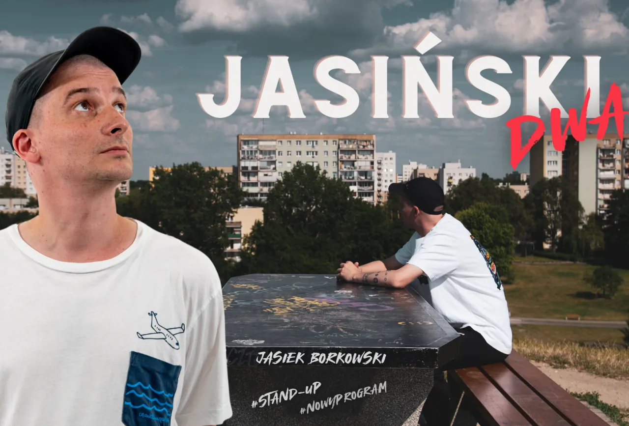 Jasiek Borkowski stand up. Dw&oacute;ch mężczyzn w czapkach z daszkiem, jeden patrzy w g&oacute;rę, drugi siedzi przy stoliku z graffiti.