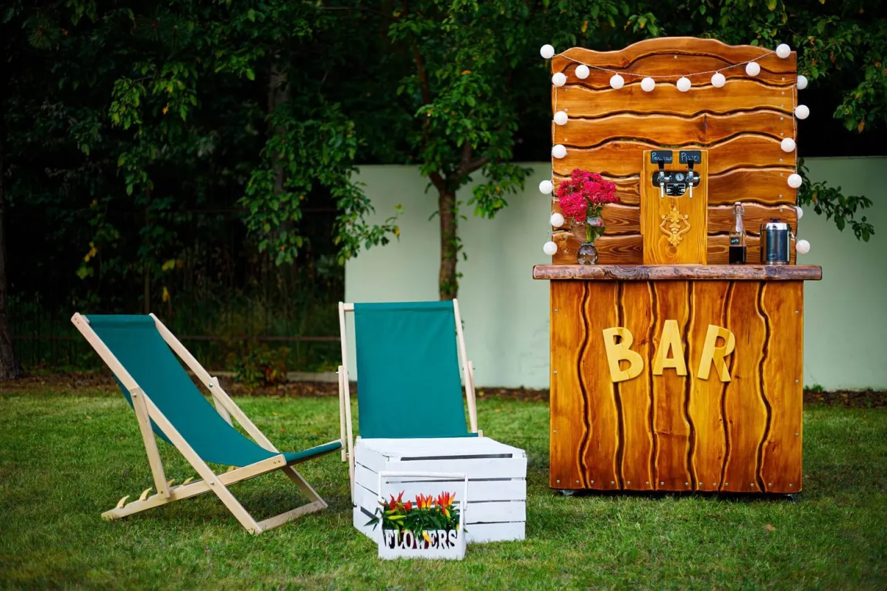 Drewniany bar z kranem i kwiatami, obok leżaki. Idealne miejsce co zamiast drink baru na letnie wieczory.