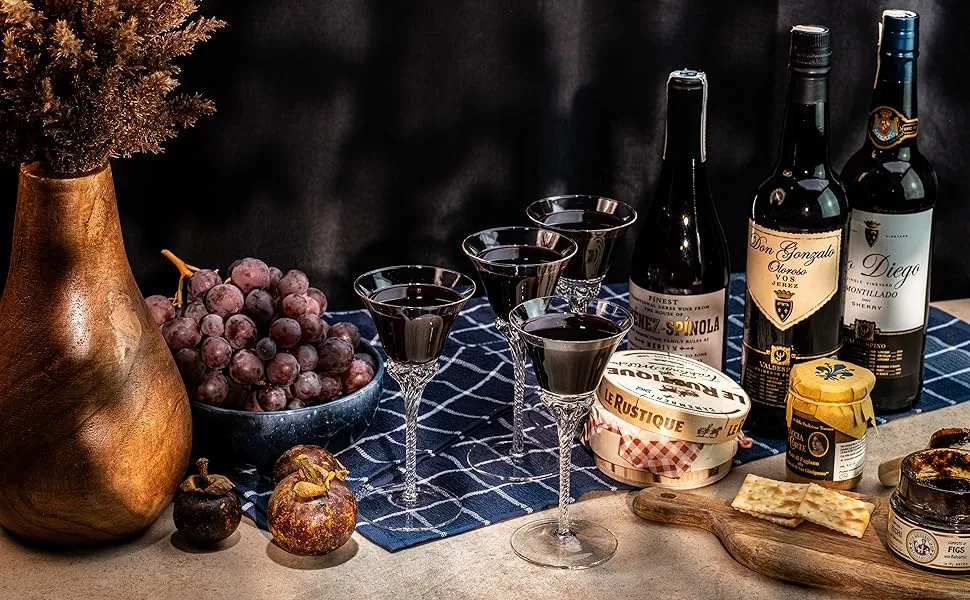 r&oacute;żne butelki win deserowych i kieliszki z winem na stole z deserami