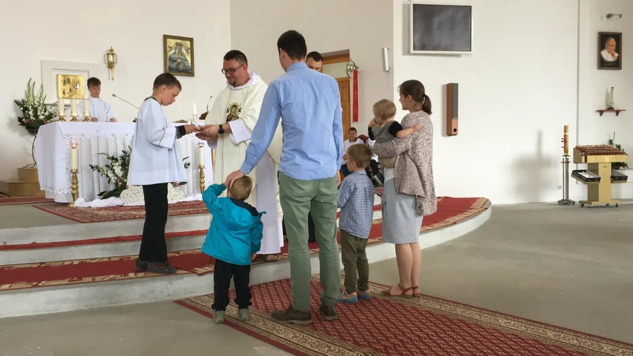 Rodzina przygotowująca się do wyjścia do kościoła, uśmiechnięte dziecko