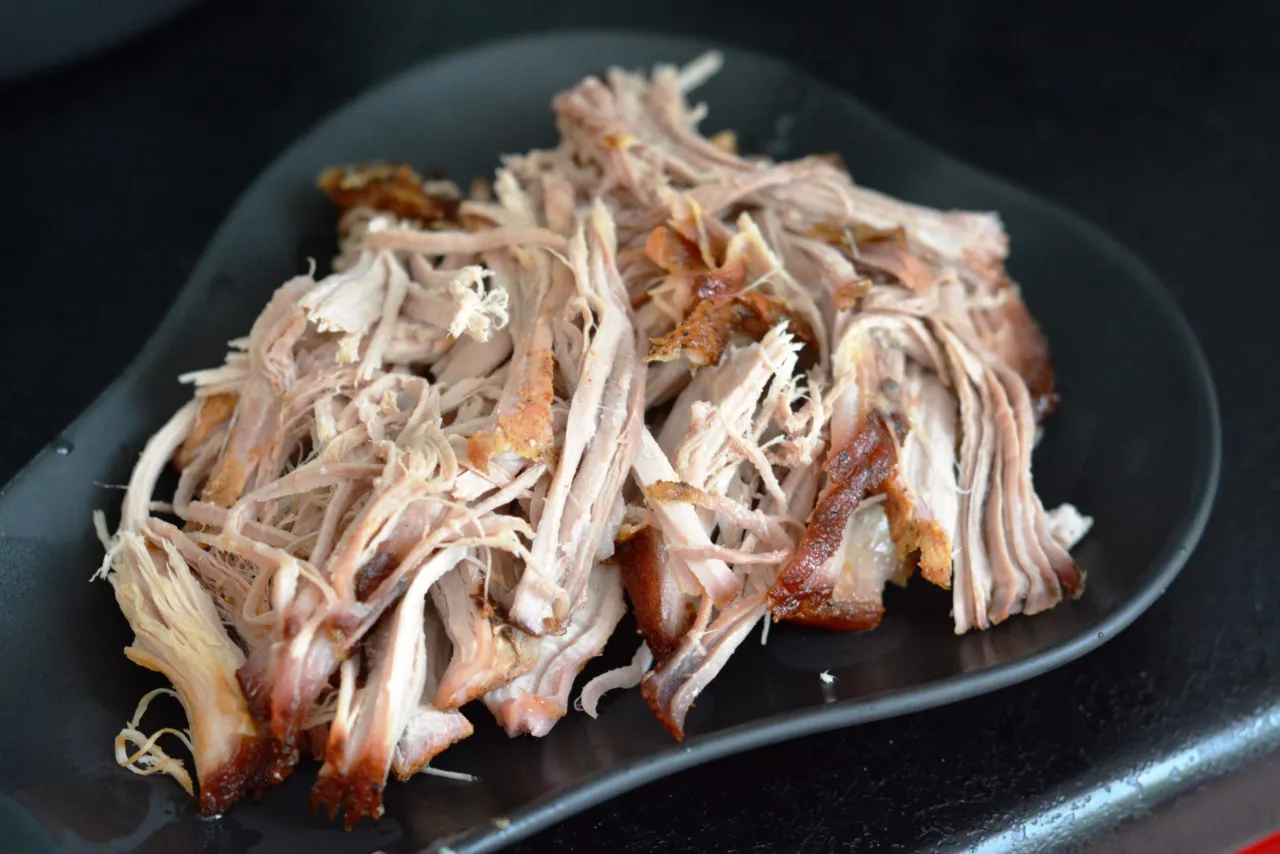 Szarpana łopatka wieprzowa na czarnym talerzu. Idealna inspiracja, co zrobić z łopatki na obiad - pyszne i soczyste mięso.