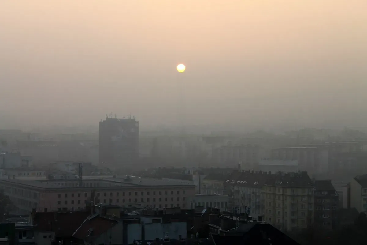 Widok miasta spowitego mgłą, słońce ledwo przebija się przez zanieczyszczenie. Takie widoki przypominają, jakie są rodzaje smogu.