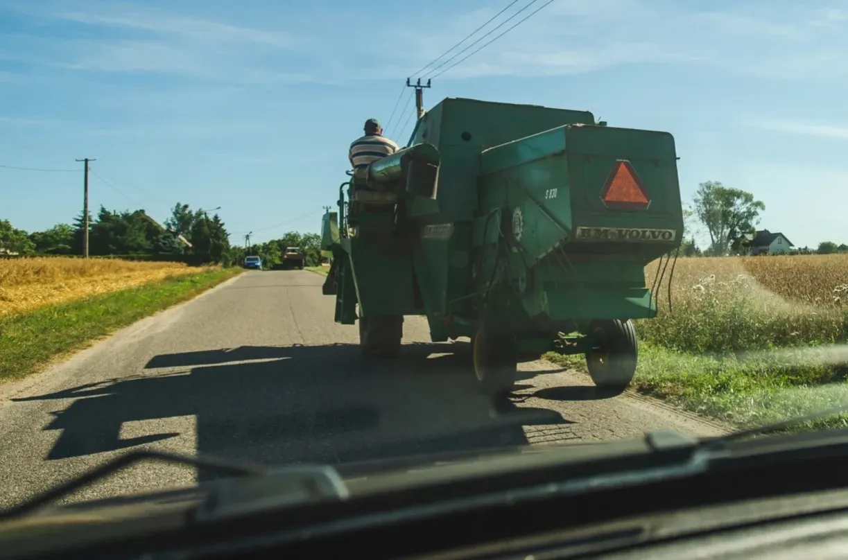 Kombajn BM-VOLVO jedzie drogą. Czy traktorkiem kosiarka można jeździć po drodze? Tak, widać to na zdjęciu.