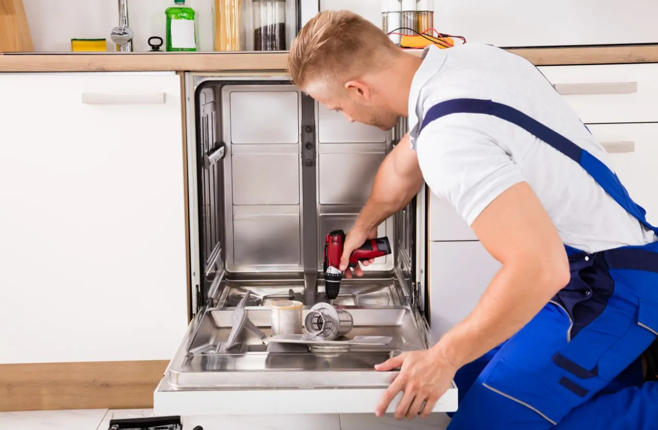 Technik montuje front do zmywarki Whirlpool, używając wiertarki.