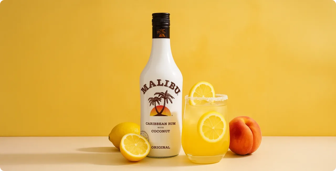 Butelka Malibu i drink z cytryną, brzoskwinią i cytrynami. Idealny Malibu przepis na lato.