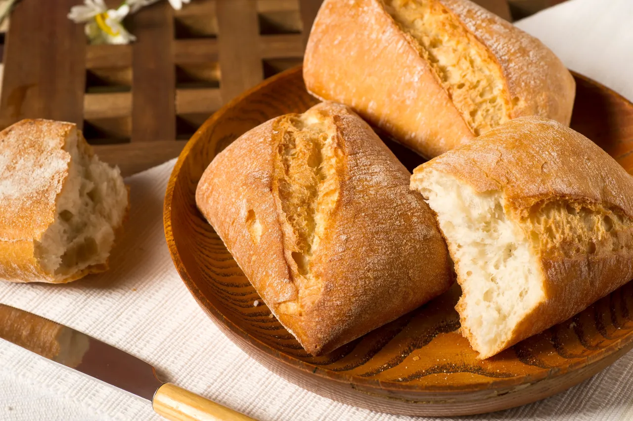 Osoba skrapiająca bułki wodą przed pieczeniem