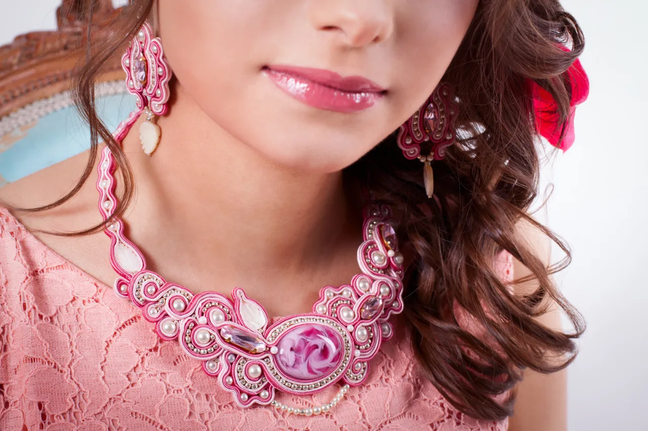Wyjątkowa biżuteria sutasz: naszyjnik i kolczyki w kolorze różowym, ozdobione perłami i kryształkami.