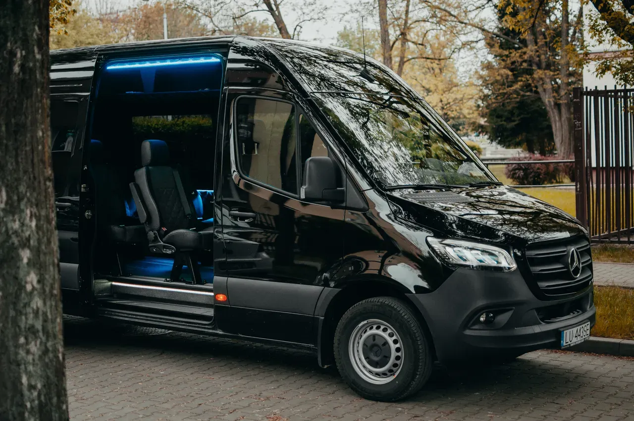 Czarny Mercedes Sprinter z niebieskim podświetleniem wnętrza, gotowy do podróży. Dowiedz się, ile kosztuje bus do Niemiec.
