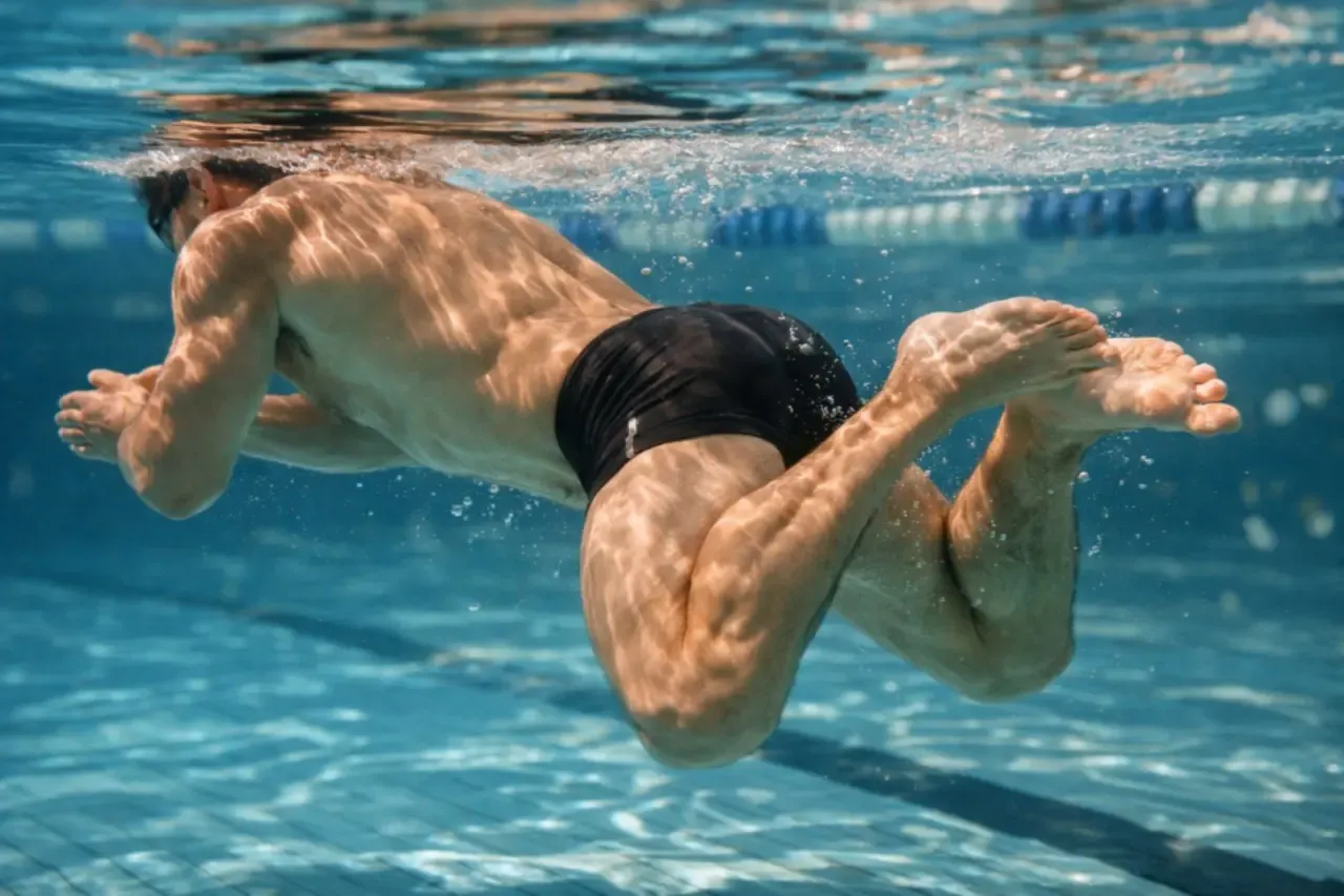 Pływanie żabką angażuje mięśnie n&oacute;g, ramion i tułowia. Widoczny mężczyzna wykonuje ten styl, pracując nad siłą i wytrzymałością.