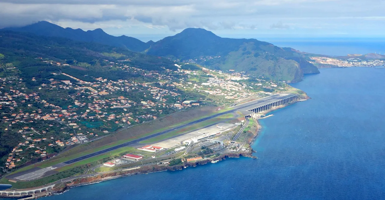 Lotnisko na Maderze, gdzie leży, z pasem startowym nad oceanem i górzystym krajobrazem w tle.