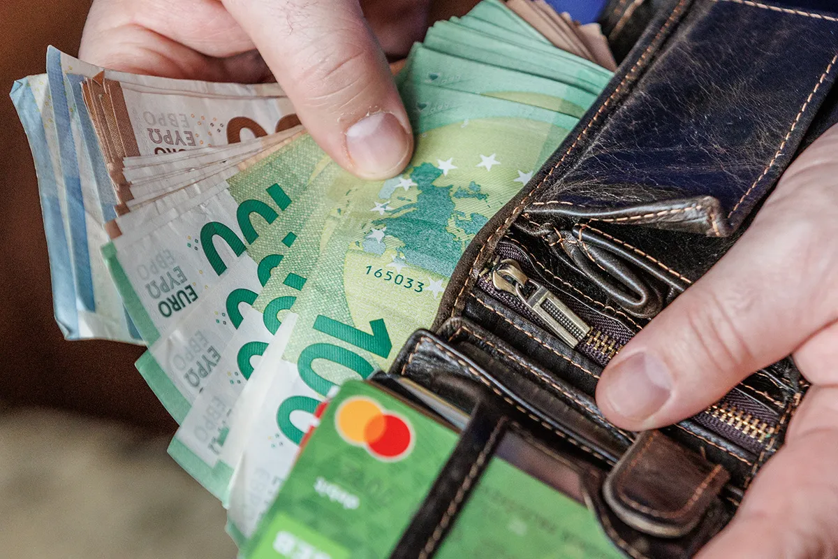 Ręka trzymająca banknoty euro i portfel. Euro to waluta na Litwie.