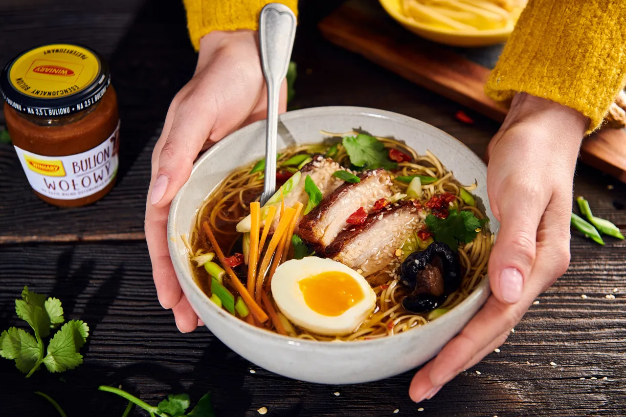 Miseczka pełna aromatycznej zupy ramen z kawałkami mięsa, jajkiem i warzywami.