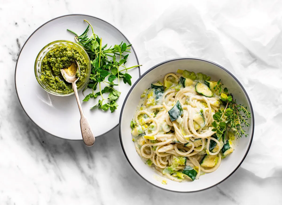 Makaron z cukinii przepis: kremowy sos, zielone warzywa i świeże zioła. Pesto obok zachęca do spróbowania.