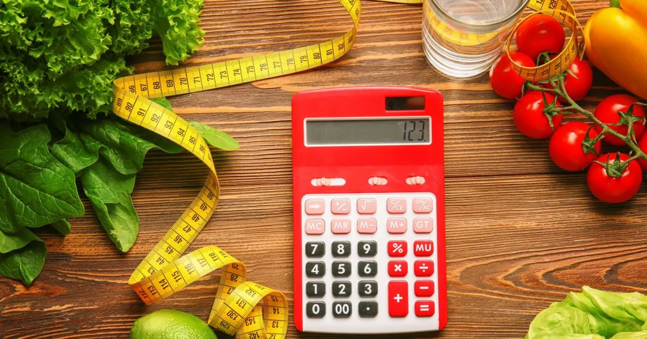 Czerwony kalkulator, miarka i warzywa na drewnianym stole. Obliczanie ile kcal na kg masy jest łatwe!