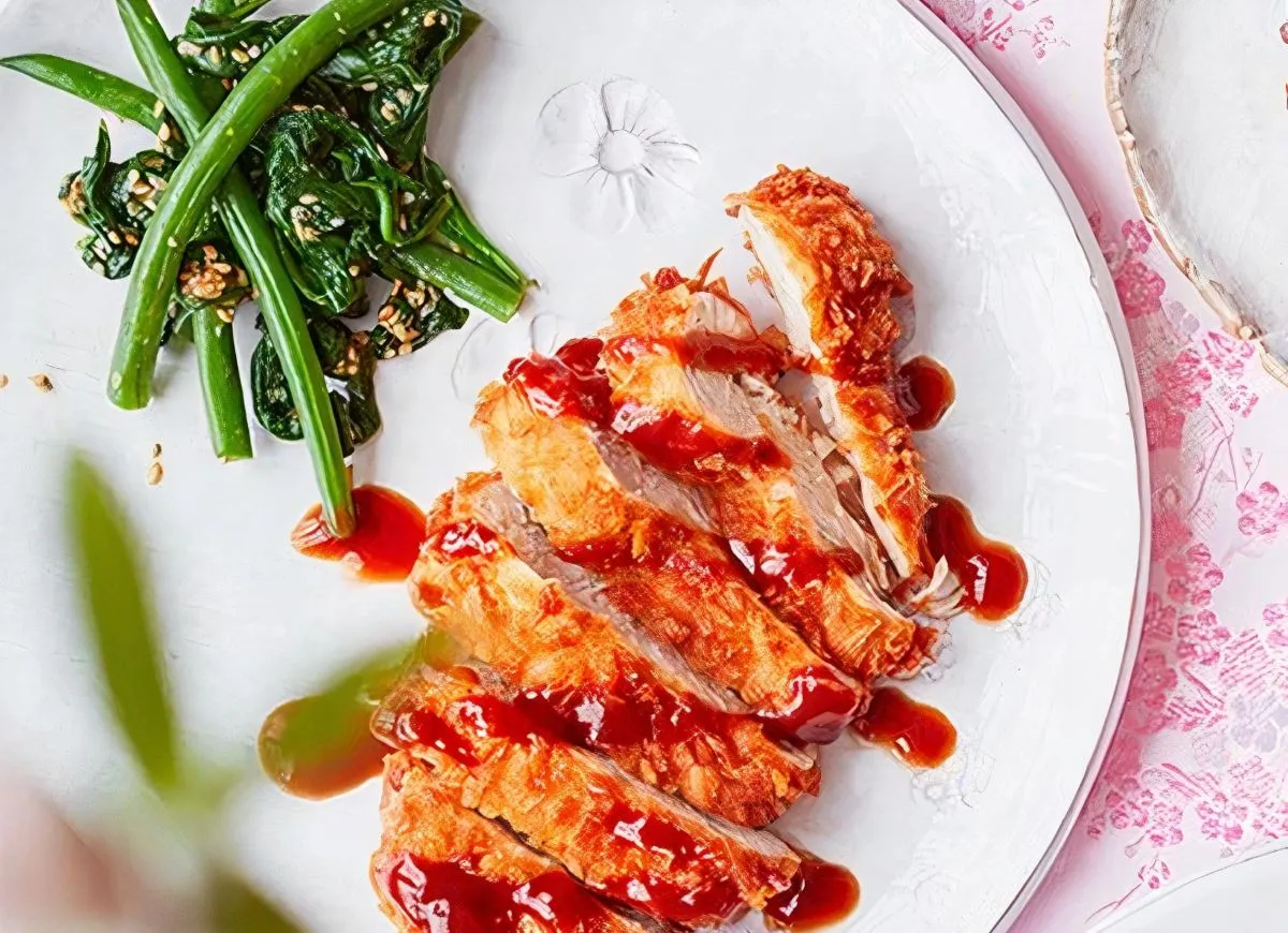 Chrupiący schabowy w panko polany sosem, podany z zielonymi warzywami i sezamem.