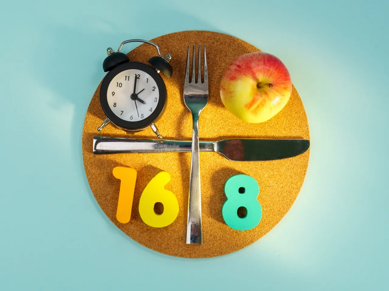 Budzik, jabłko, sztućce i cyfry 16:8 symbolizują post przerywany. Ile schudłam? Czas pokaże!