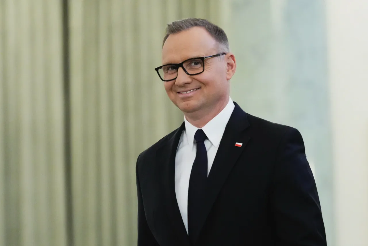 Uśmiechnięty Andrzej Duda w garniturze, z polską flagą na klapie. Ile lat ma Duda? To pytanie nurtuje wielu.