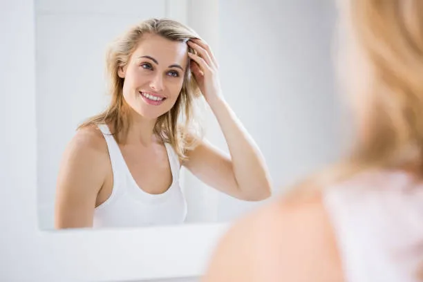 kobieta analizująca swoje włosy i skórę głowy w lustrze