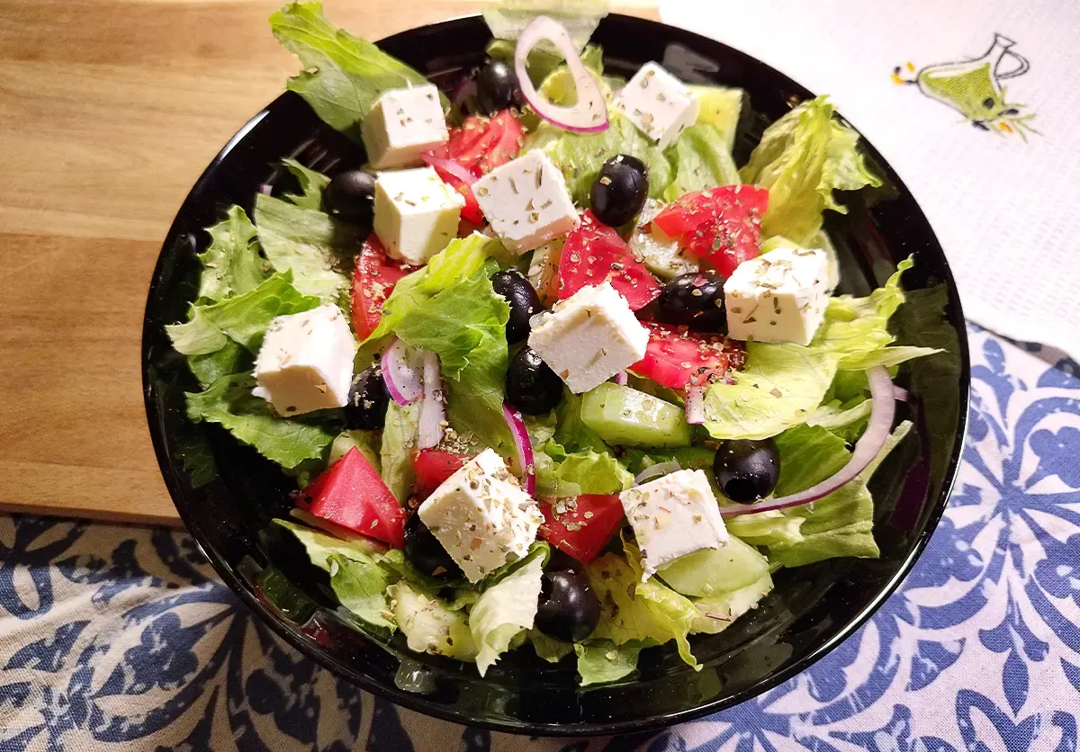 Sałatka grecka z fetą, pomidorami, ogórkiem i oliwkami, posypana oregano. Idealna do lekkich dań.