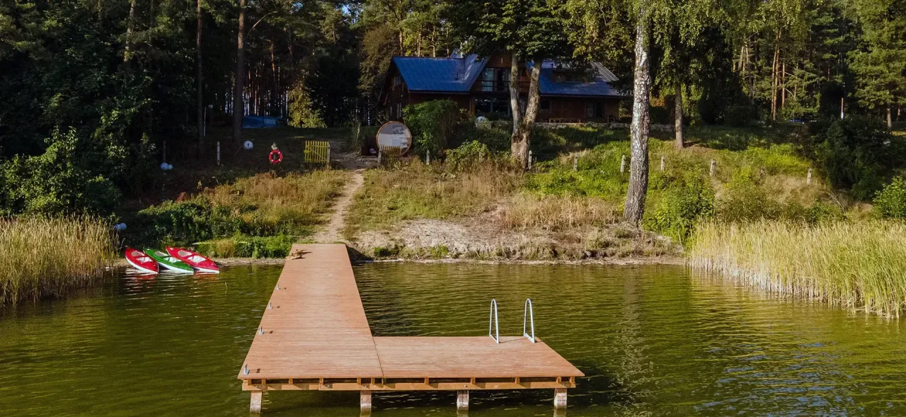 Idealne miejsce, gdzie na ryby z noclegiem Wielkopolska. Drewniany pomost, kajaki i domek w lesie nad jeziorem.
