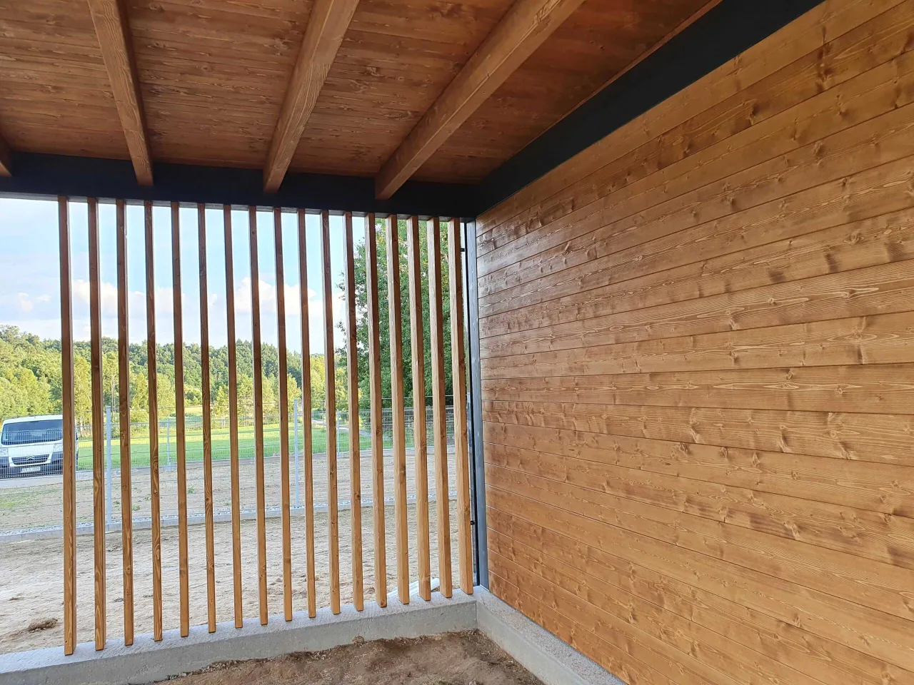 Drewniane deski i pionowe słupki to stylowy spos&oacute;b, czym zabudować altanę, tworząc przytulną przestrzeń.