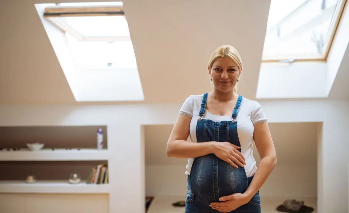 Kobieta w ciąży wietrząca pokój po malowaniu