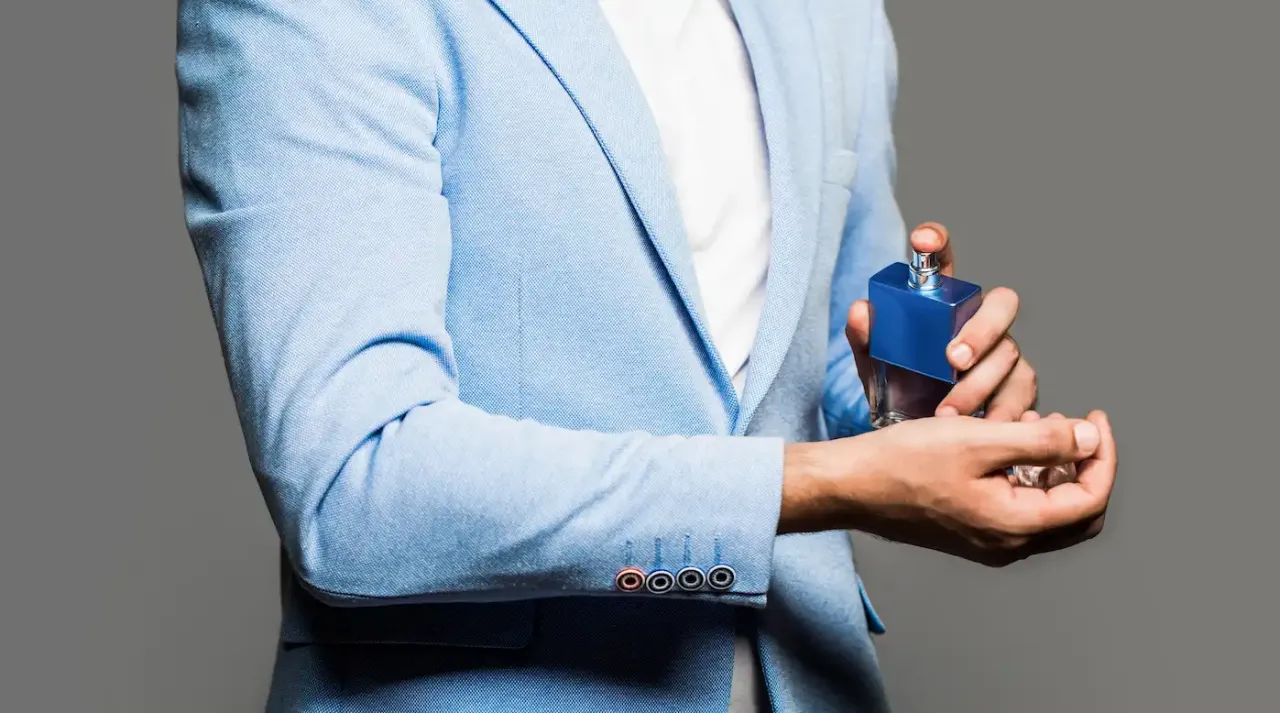 mężczyzna aplikujący perfumy na nadgarstek