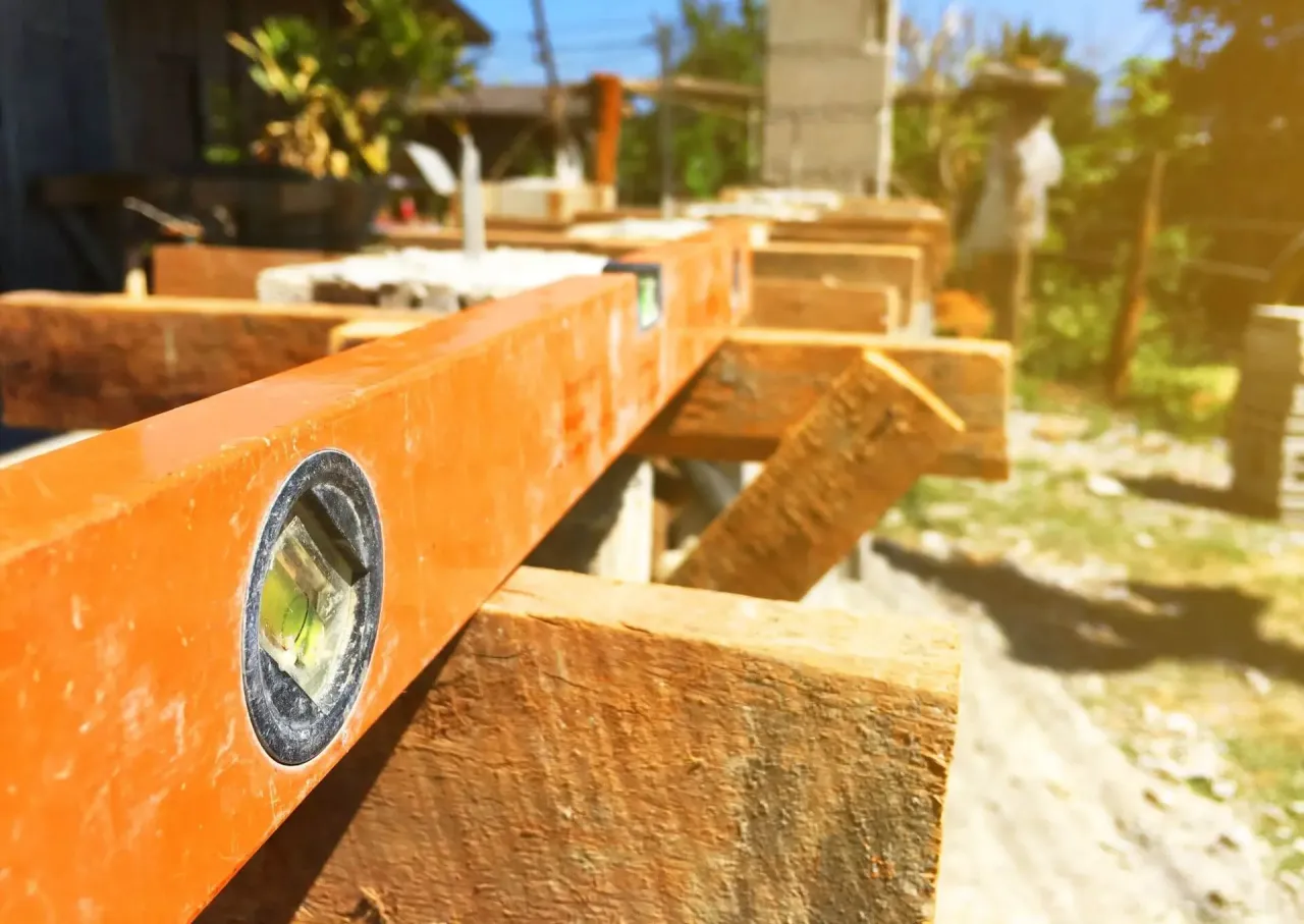 Poziomica na drewnianej konstrukcji. Zastanawiasz się, ile kosztuje budowa małego domu z drewna?