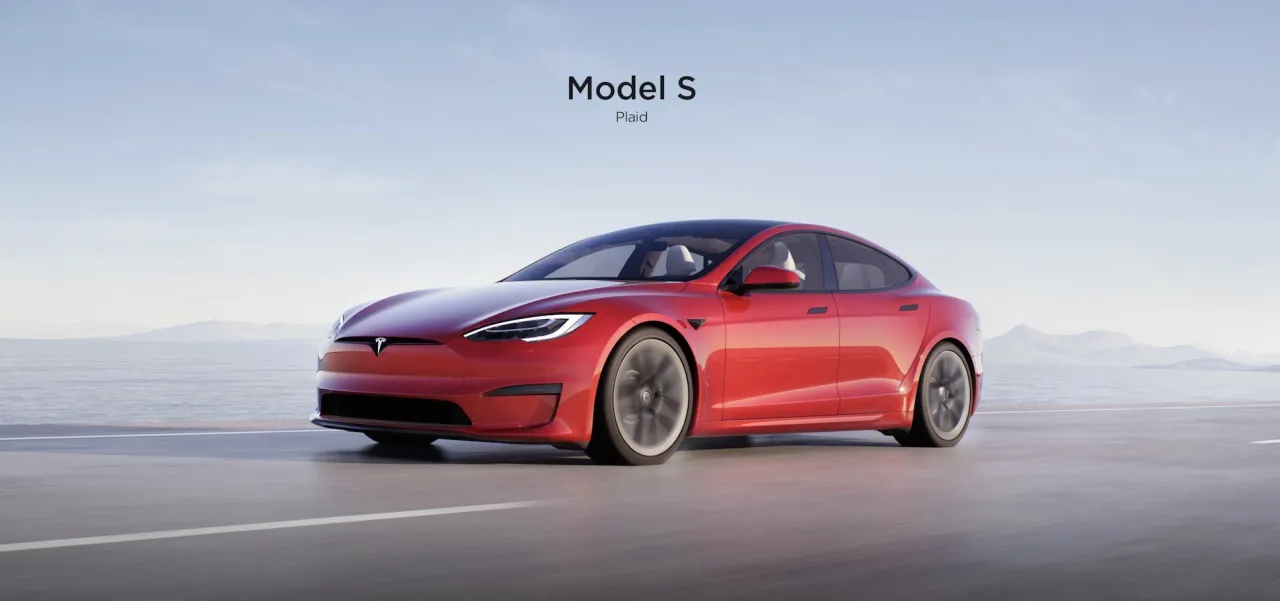Czerwony Tesla Model S Plaid, z imponującą mocą, pędzi po pustej drodze z widokiem na morze i góry.