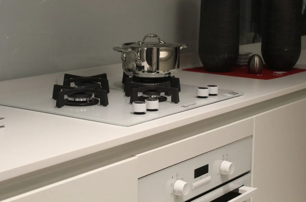 Nowoczesna kuchnia: montaż płyty gazowej nad piekarnikiem elektrycznym. Stalowy garnek na palniku.