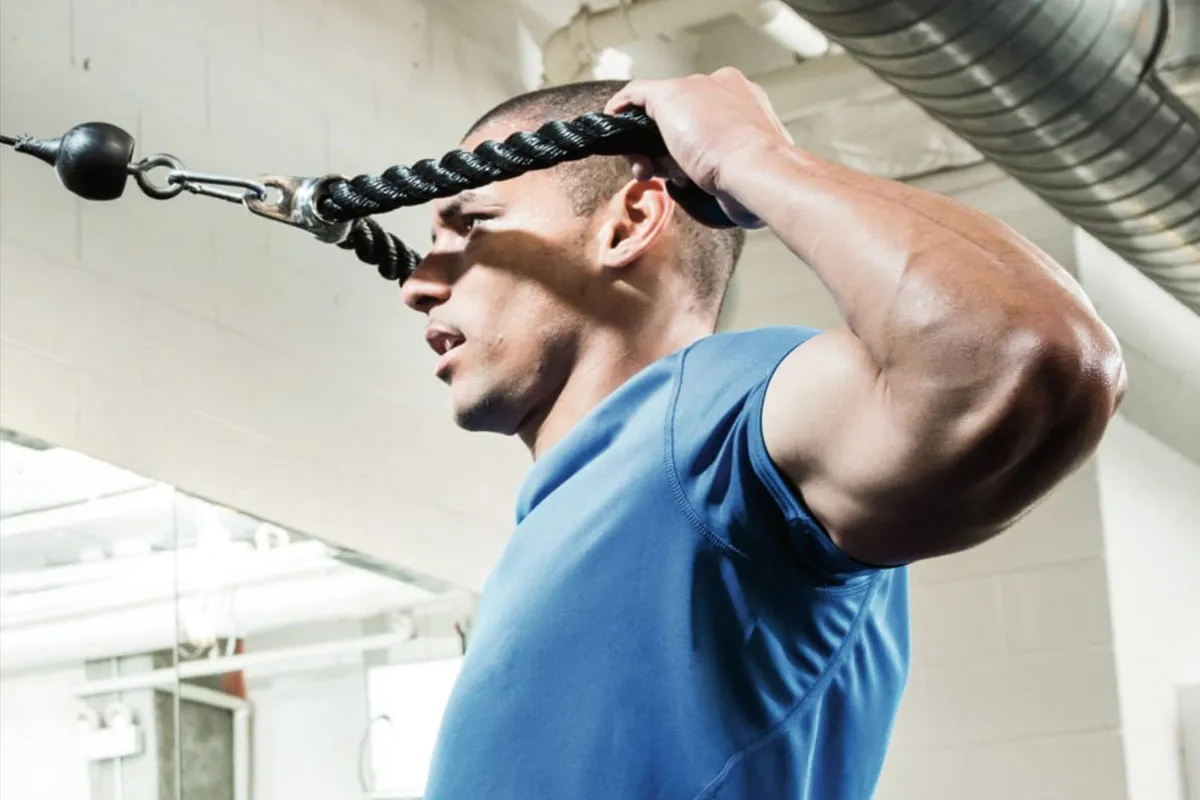 Mężczyzna wykonuje ćwiczenia na tył barku z użyciem wyciągu.