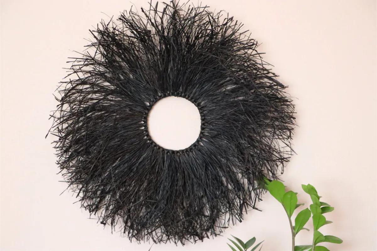 Czarna, okrągła dekoracja z rafii, przypominająca słońce lub pióropusz. Idealna do wnętrz boho. Gdzie kupić rafia dekoracyjna?