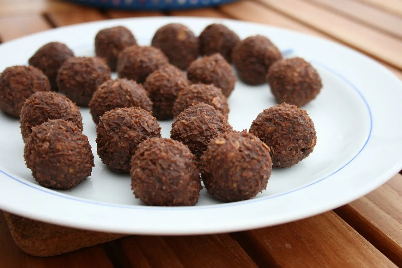 Na talerzu ułożono wiele czekoladowych kulek mocy, wyglądających jak pyszne domowe pralinki.